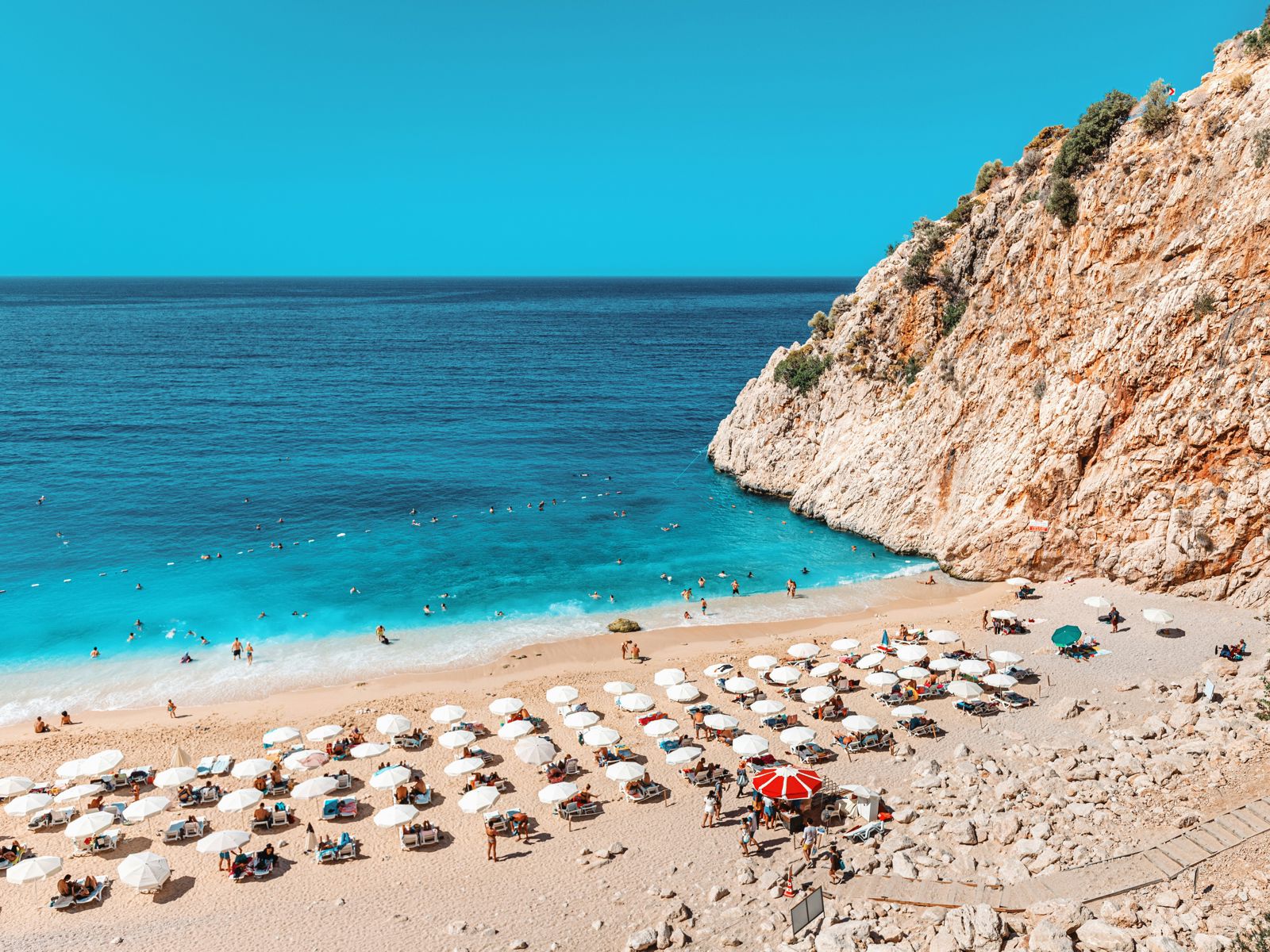 Beach with cliffs and sun loungers facing blue sea