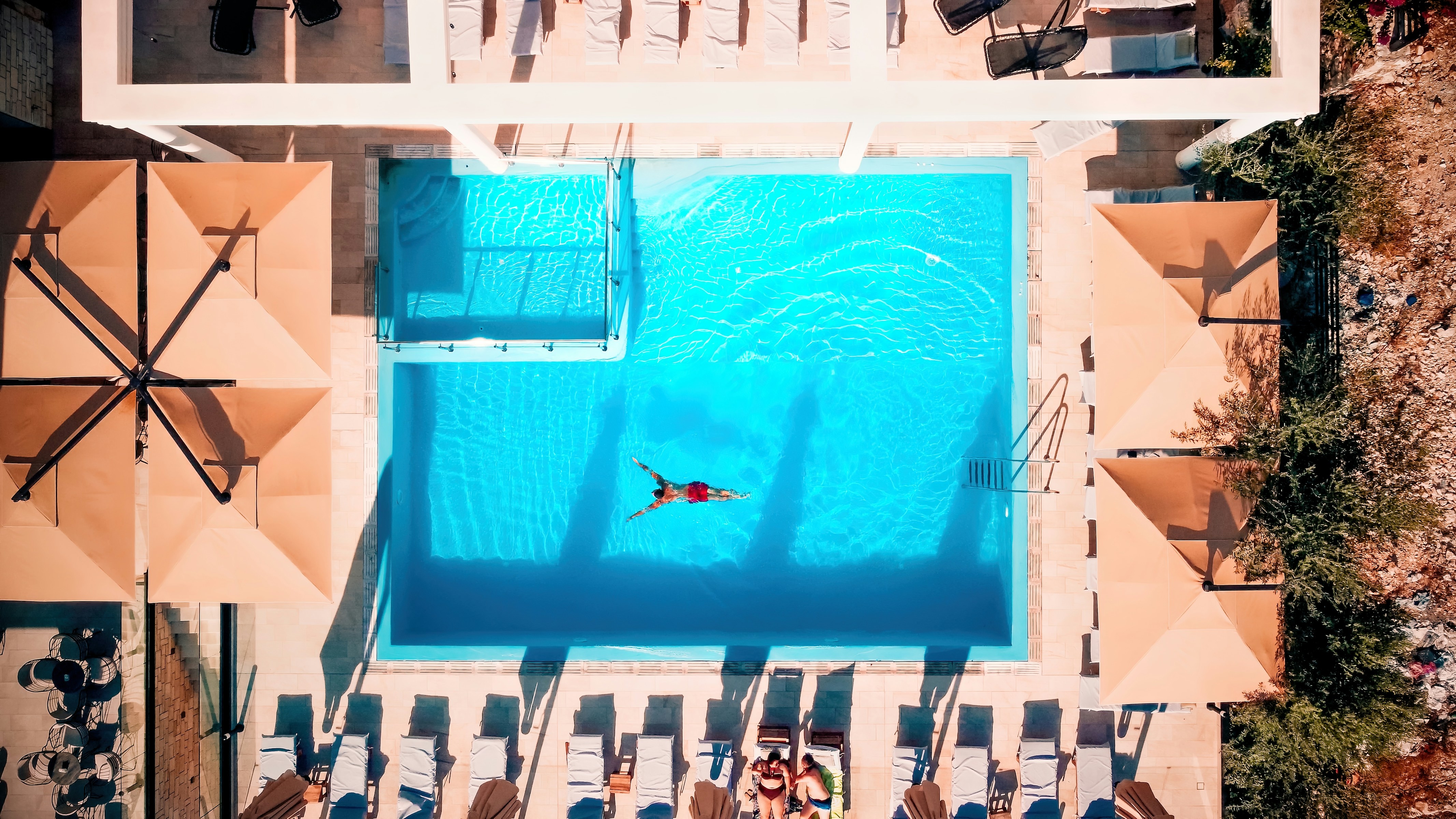 Utsikt ovenfra over et hotell med basseng og en mann som svømmer