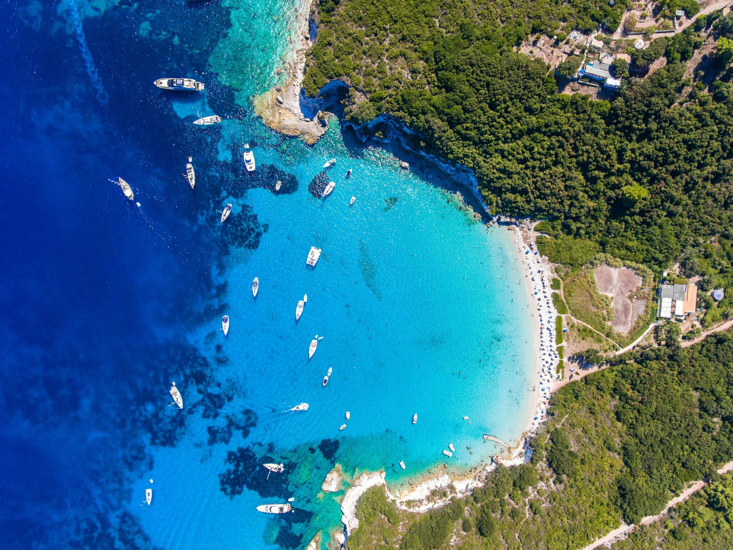 Top view of blue sea meeting white sand beach on a Greek island