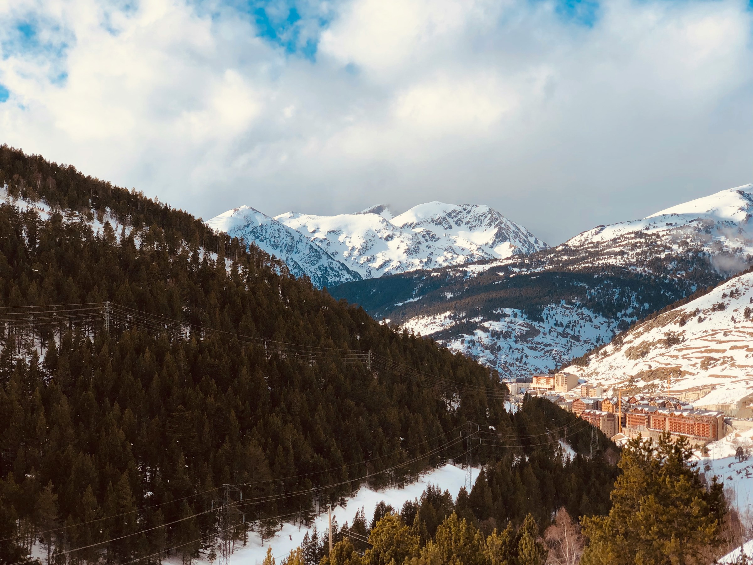 View of snow-capped mountain ranges in Grandvalira, Andorra but a ski resort below