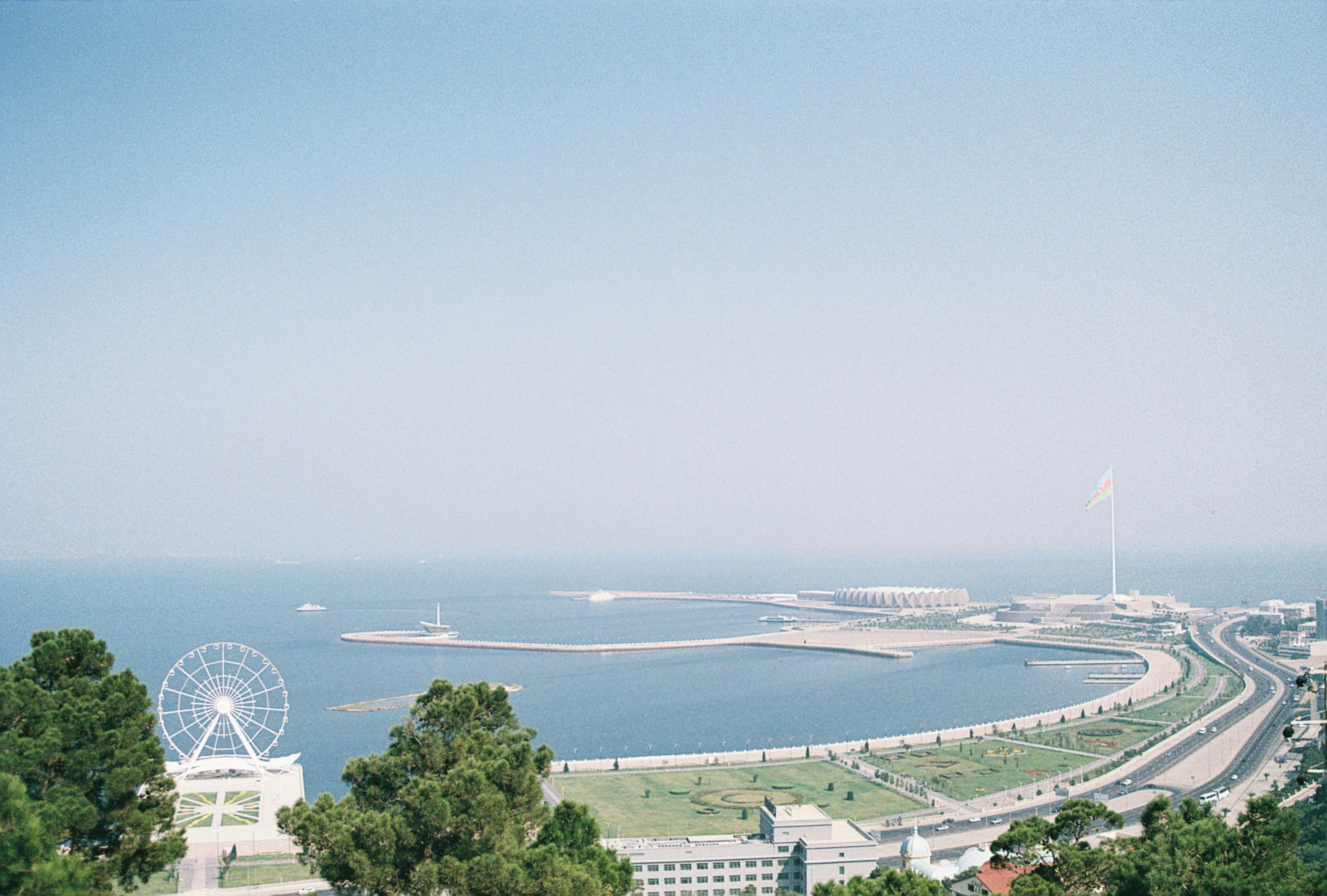 Kysthavn med strand i Baku møter blått hav og tåkeblå himmel i bakgrunnen