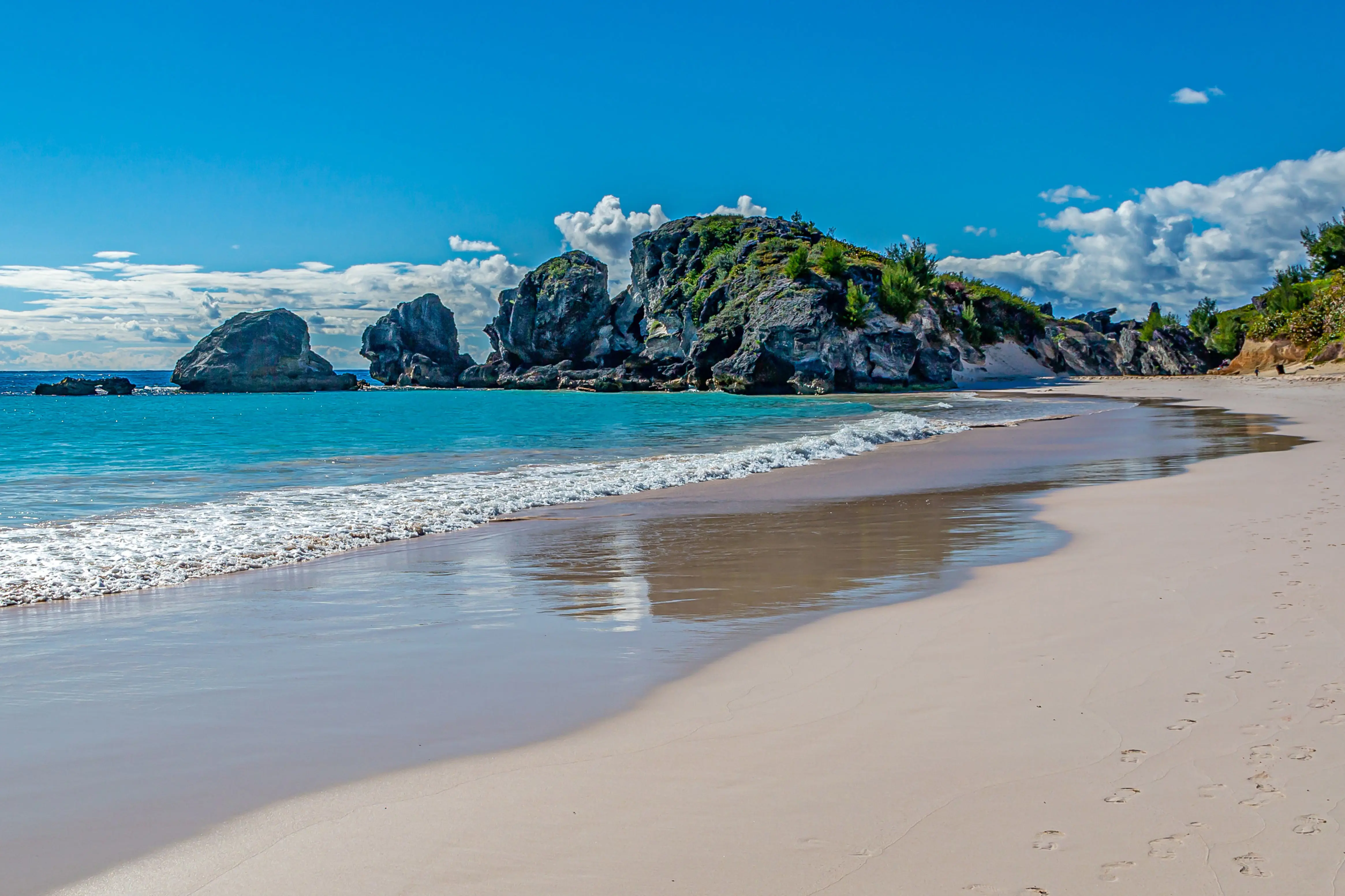 Reis til Bermuda - Vakker rolig hvit strand med turkisblått vann med steiner og blå himmel i bakgrunnen