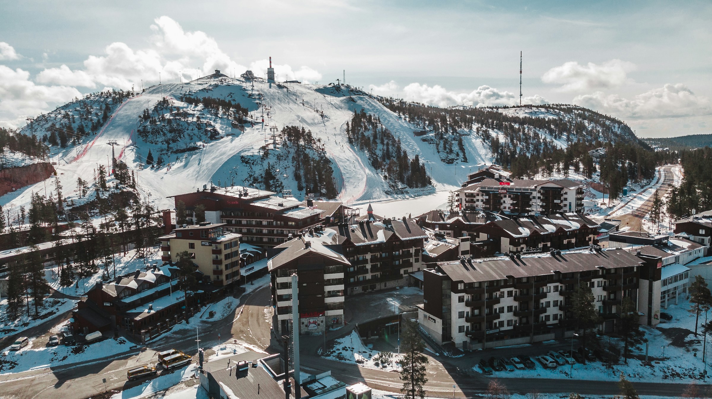 View of ski slope in Ruka, Finland leading down to a resort and buildings, all covered in snow