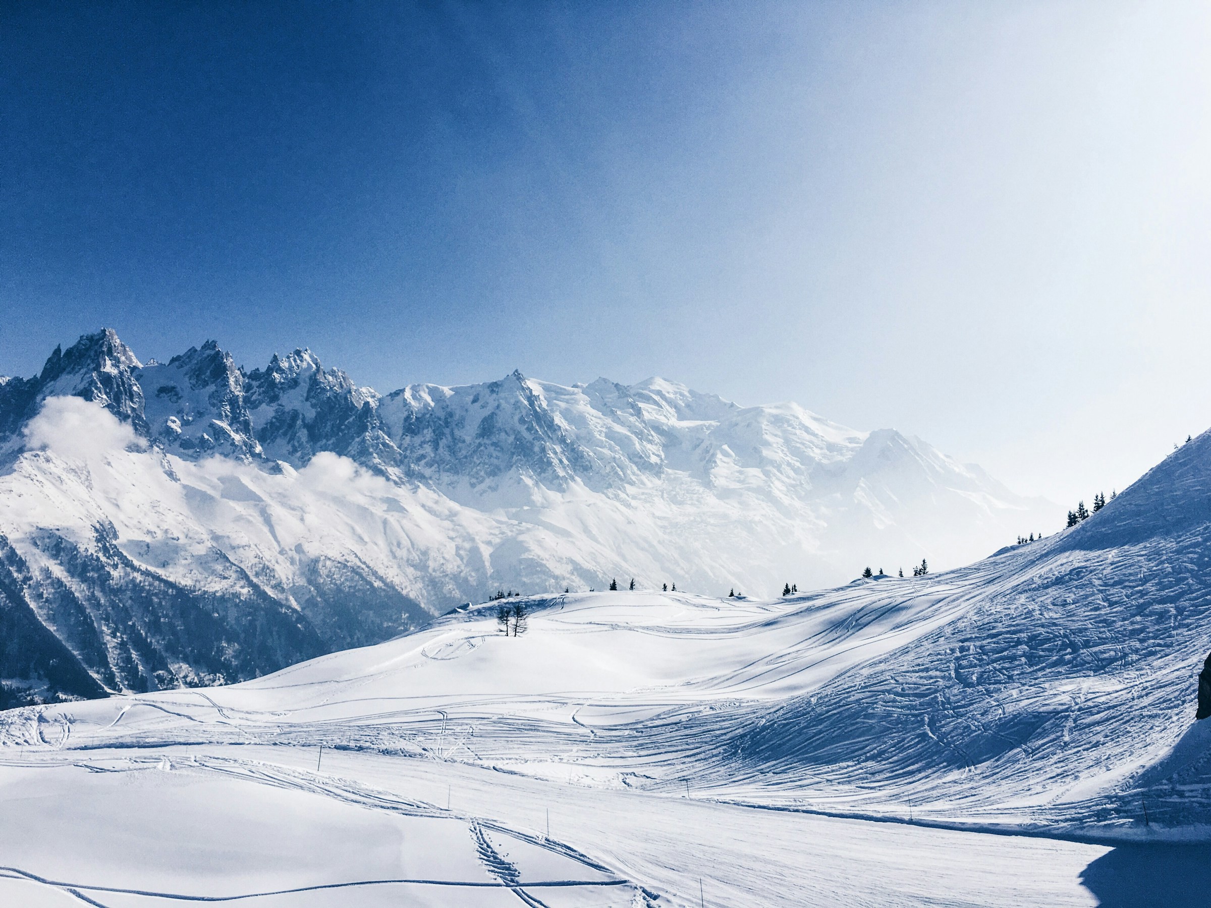 View of winter wonderland and snow-capped valleys and mountains in Chamonix, France with blue sky in the background