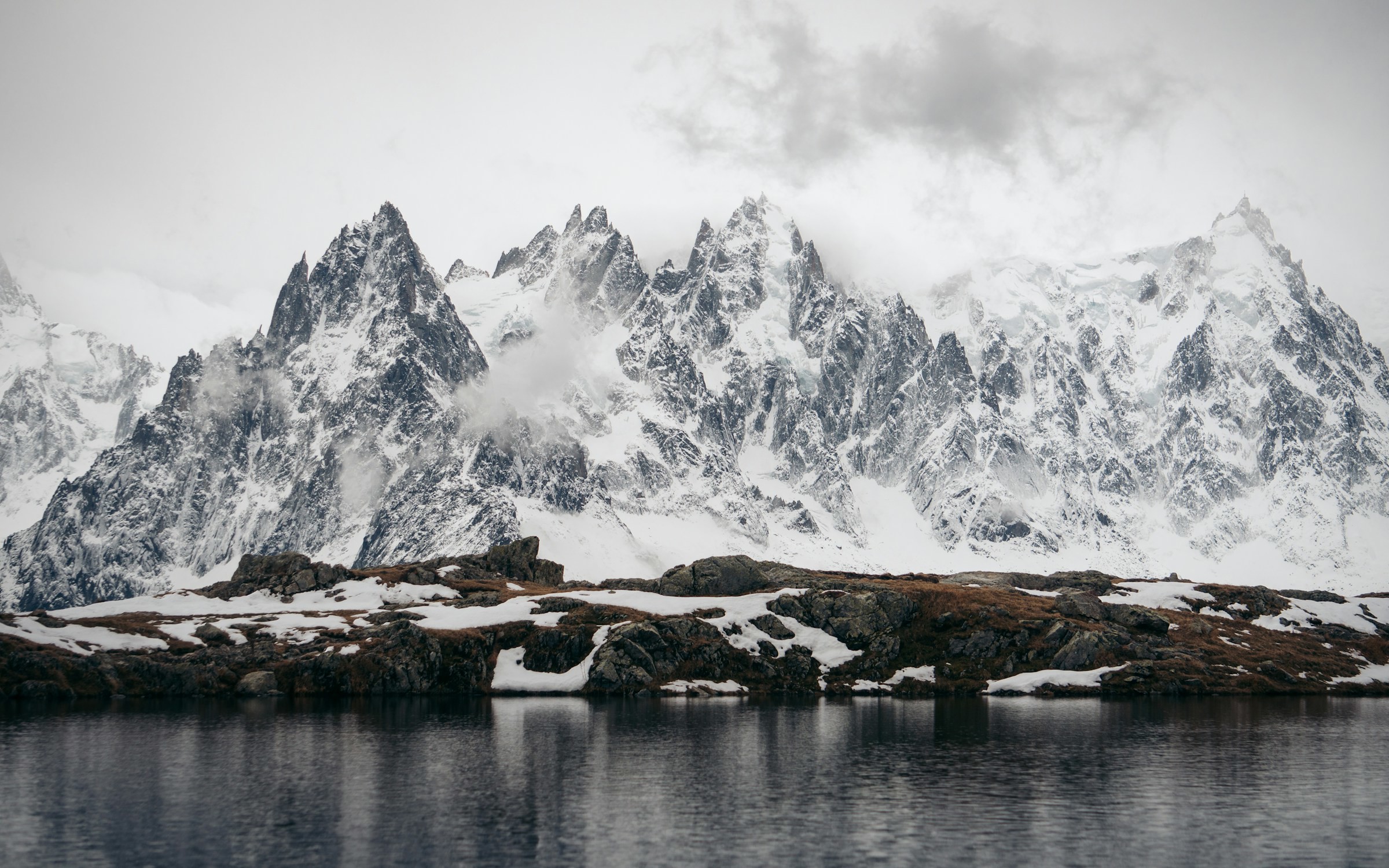 Lake at the foot of a mighty snow-capped mountain against a white sky in Chamonix, France