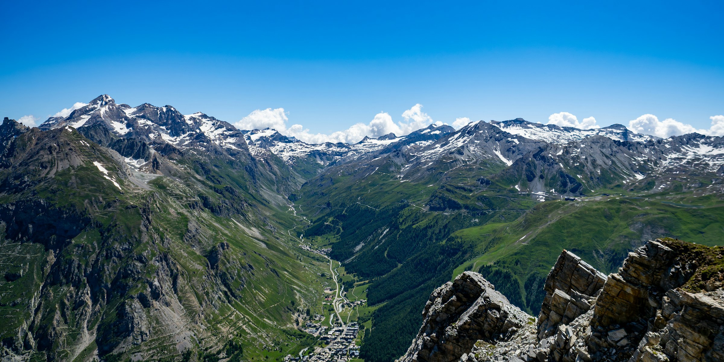 Mountain scenery with snow-capped peaks and a valley under a clear blue sky in the Val d'Isére.