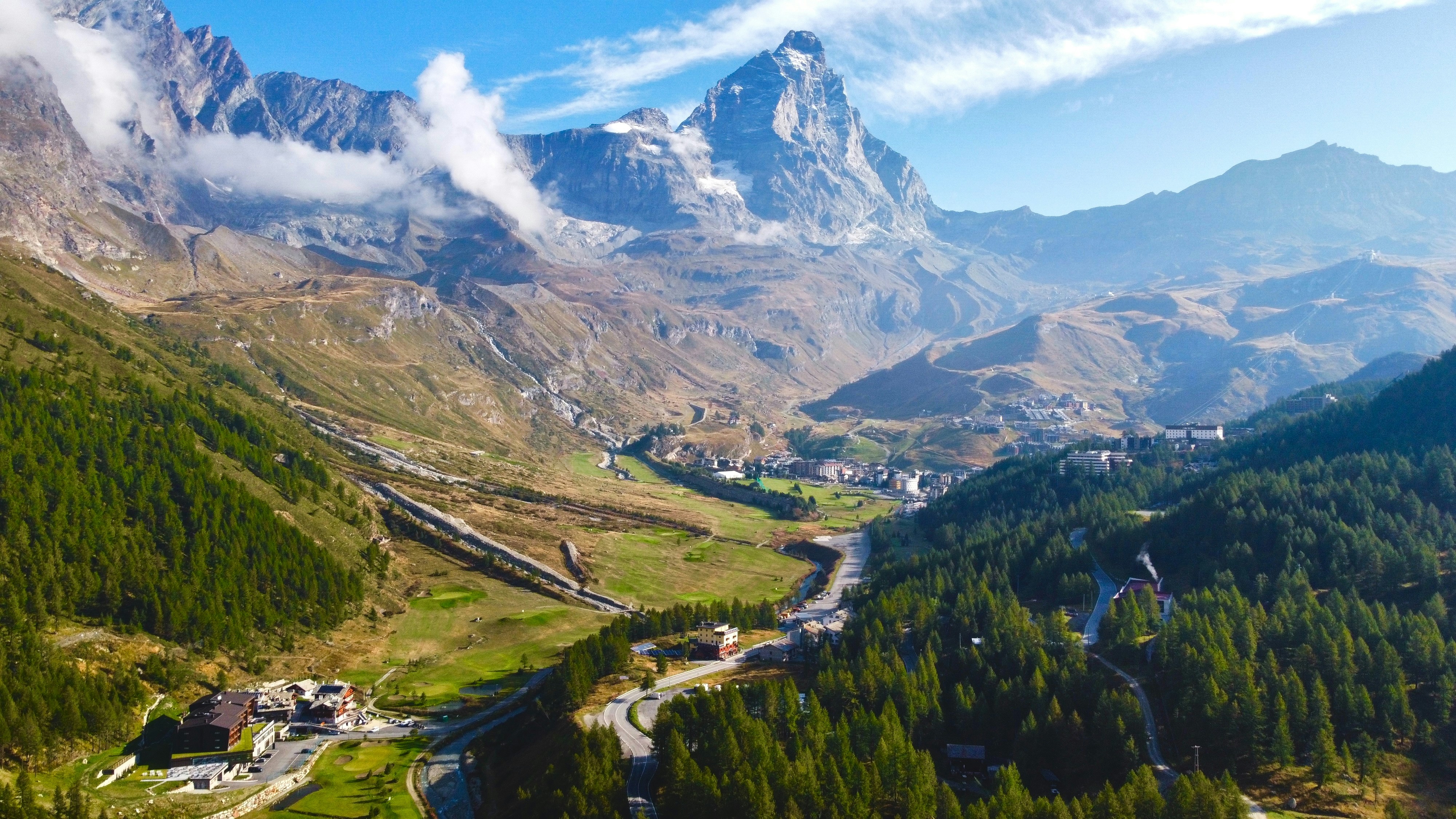 Travel to Cervinia - Mountain scenery with picturesque village and clouds around the mountain peaks under clear skies.