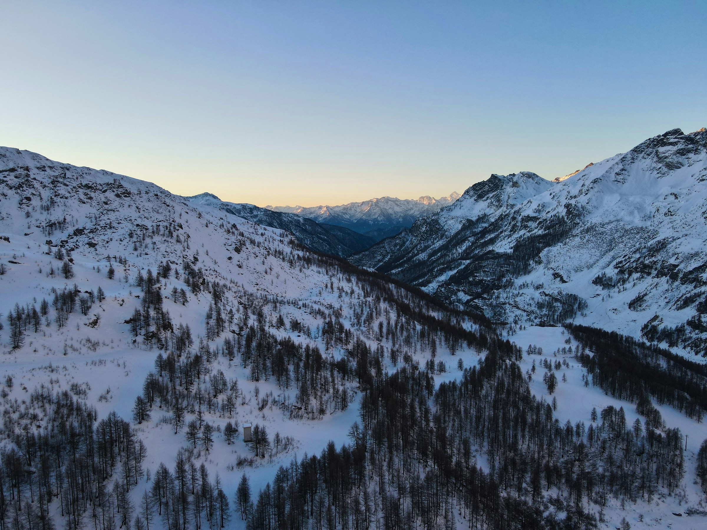 Winter landscape at sunset with snow-capped mountains and forest in alpine setting in Cervinia.