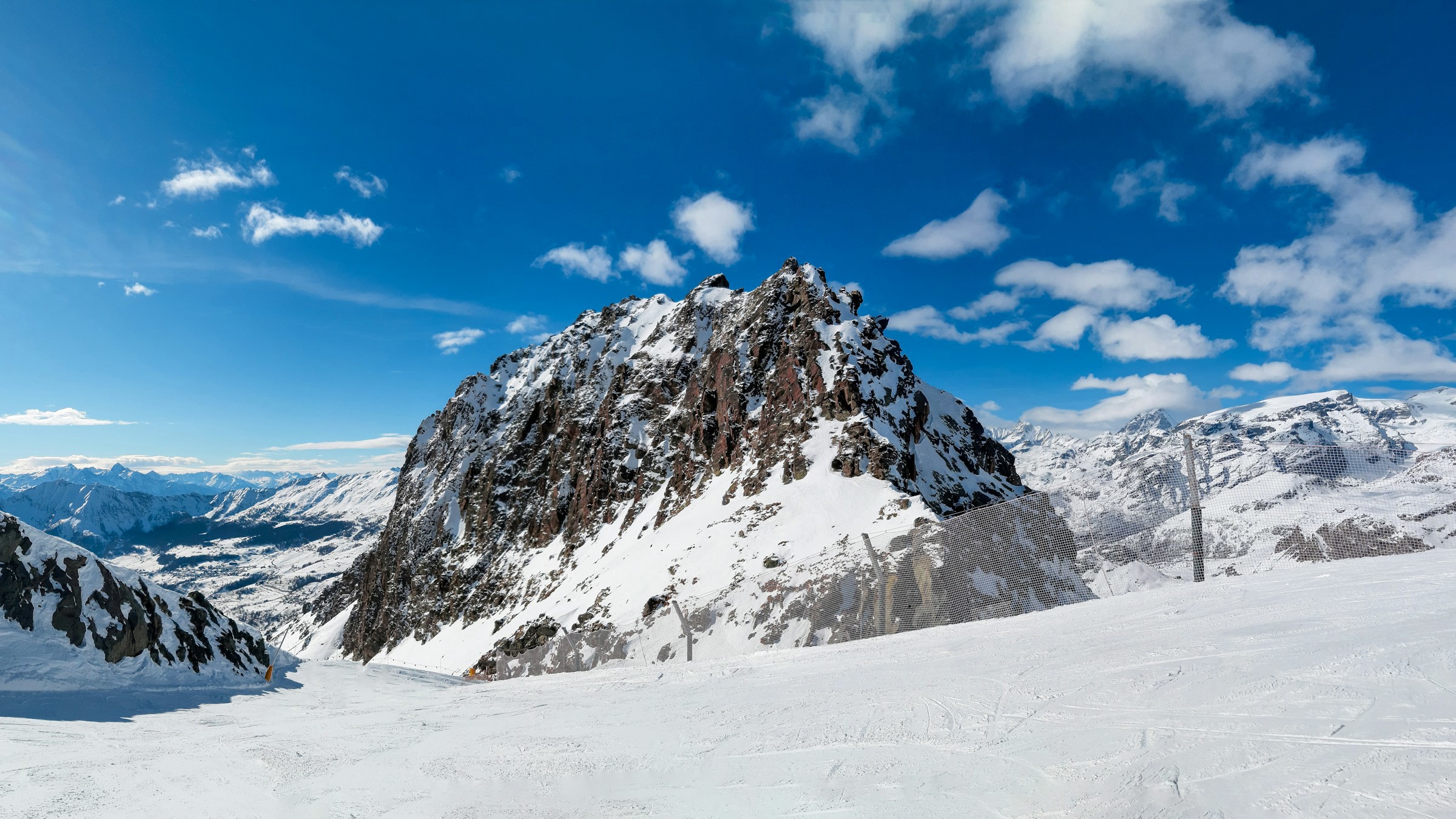 Snow-capped mountains on a ski slope with blue sky and forest in the background in Champoluc, Italy