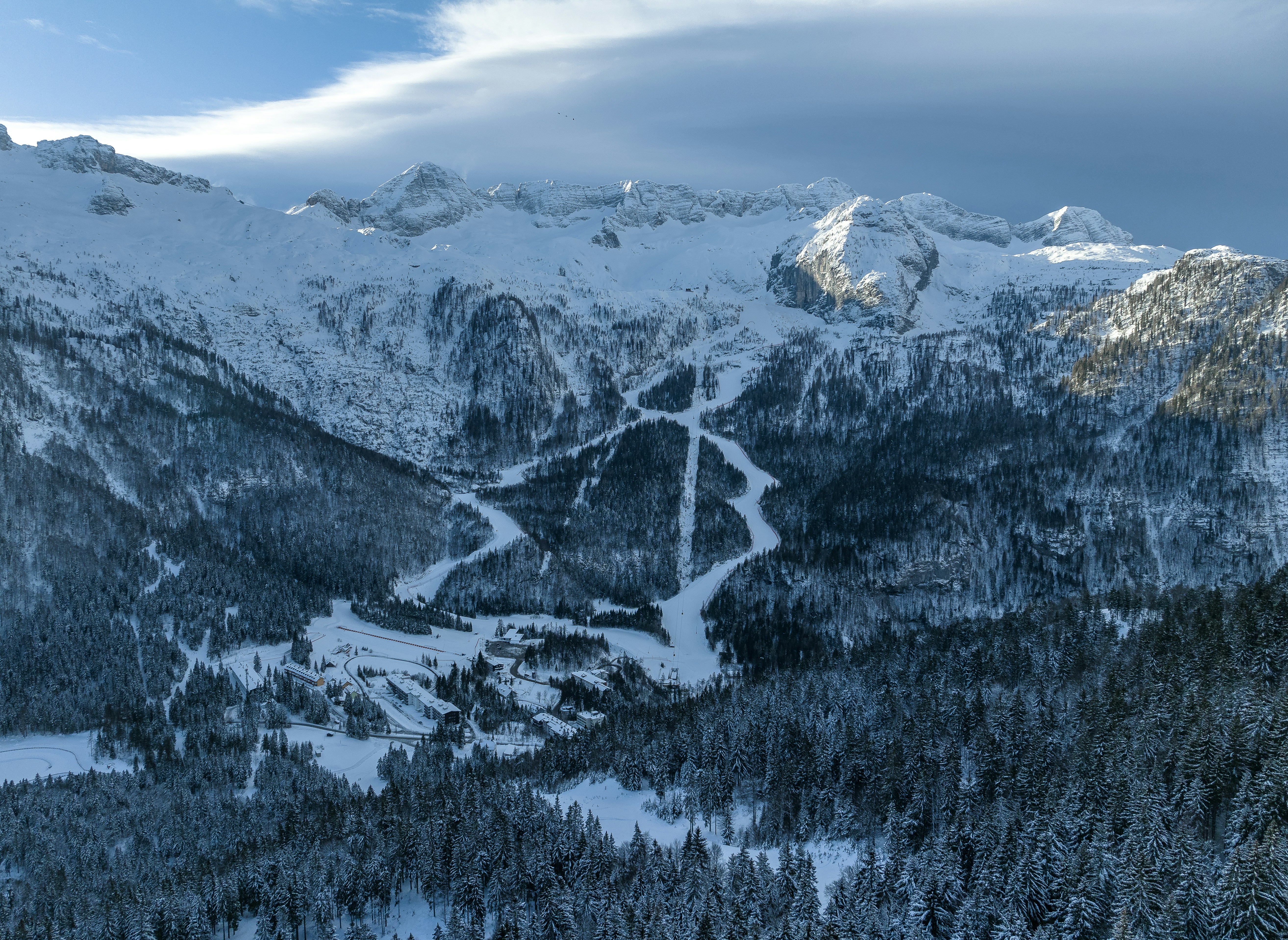 Travel to Val Gardena - Bird's-eye view of snow-capped mountains and cliffs down to a valley and a ski resort