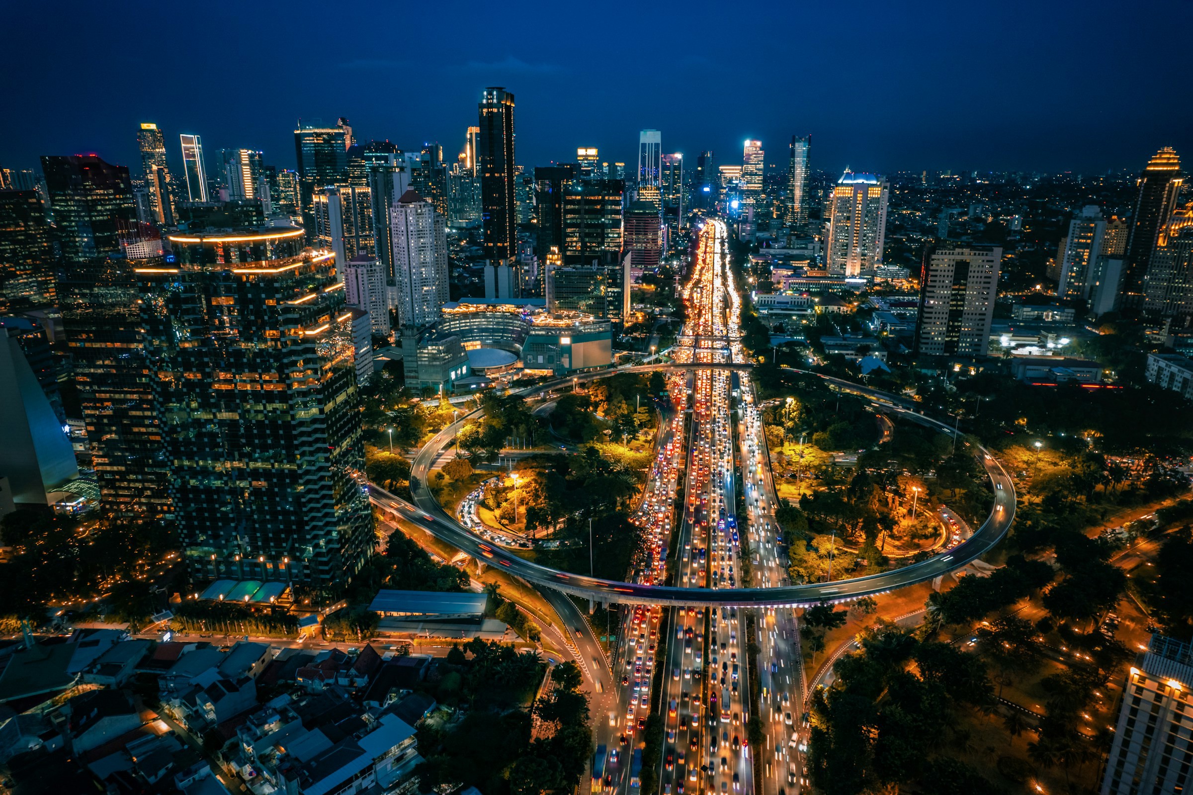 Utsikt over Jakarta by om natten med byen opplyst av lys, trafikk og skyskrapere i bakgrunnen