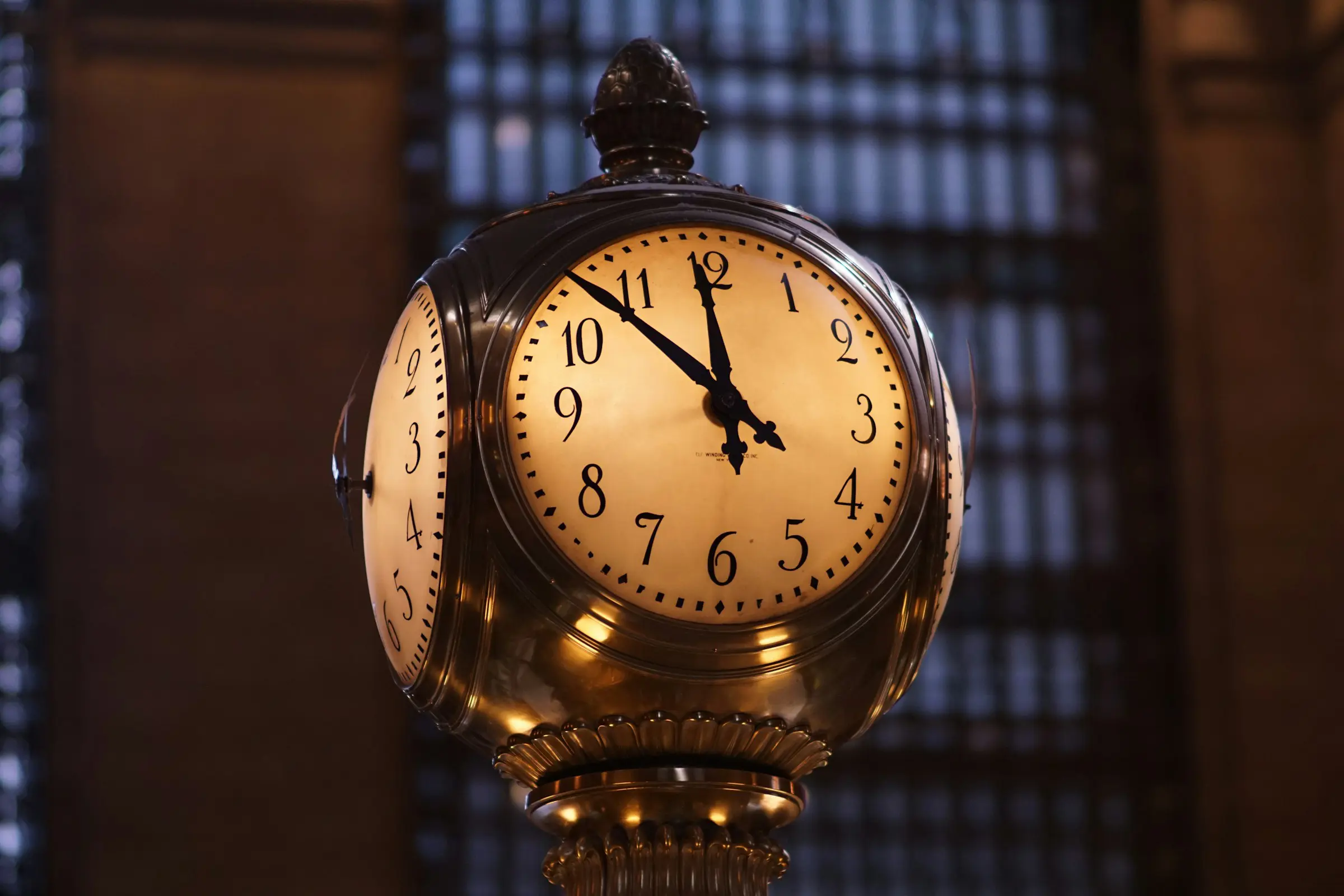 A lavish clock inside Grand Central Terminal displays the time as 10:10, set against a dimly lit architectural backdrop