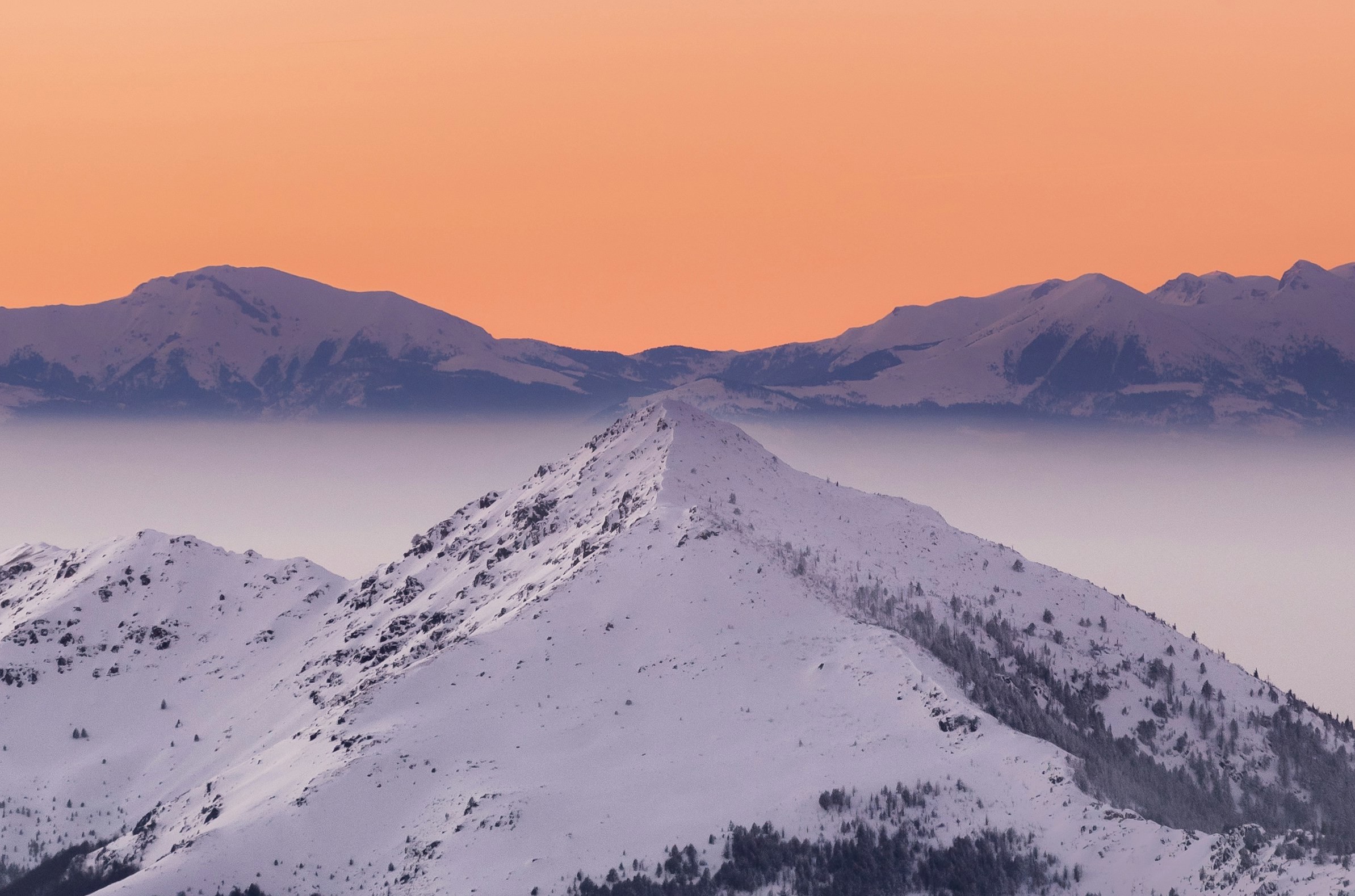 Sunset over a mountain and snow-covered slopes in Brezovica with an orange sky in the background