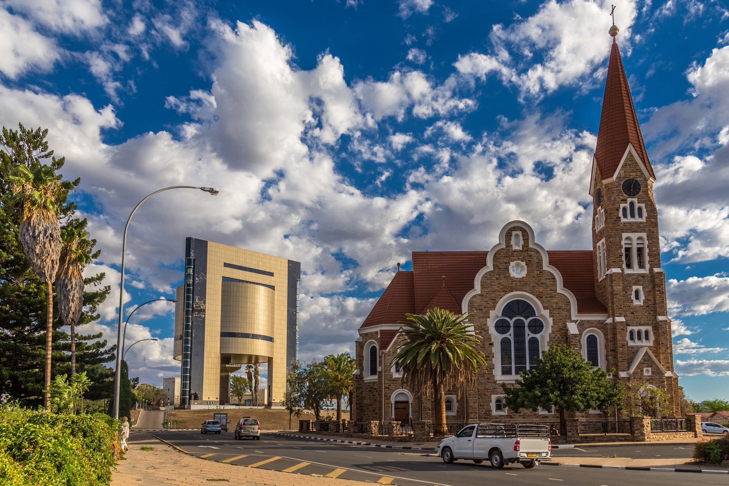 Vakker mursteinskirke i Windhoek med grøntområder rundt og blå himmel med skyer i bakgrunnen