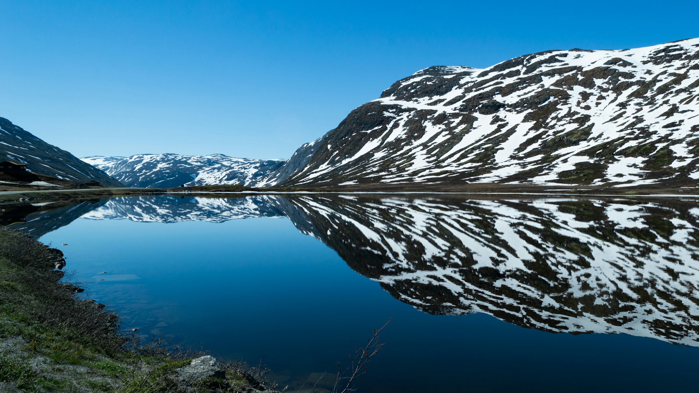 Tranquil lake leading up to the Norwegian fjord in Hemsedal with blue sky in the background