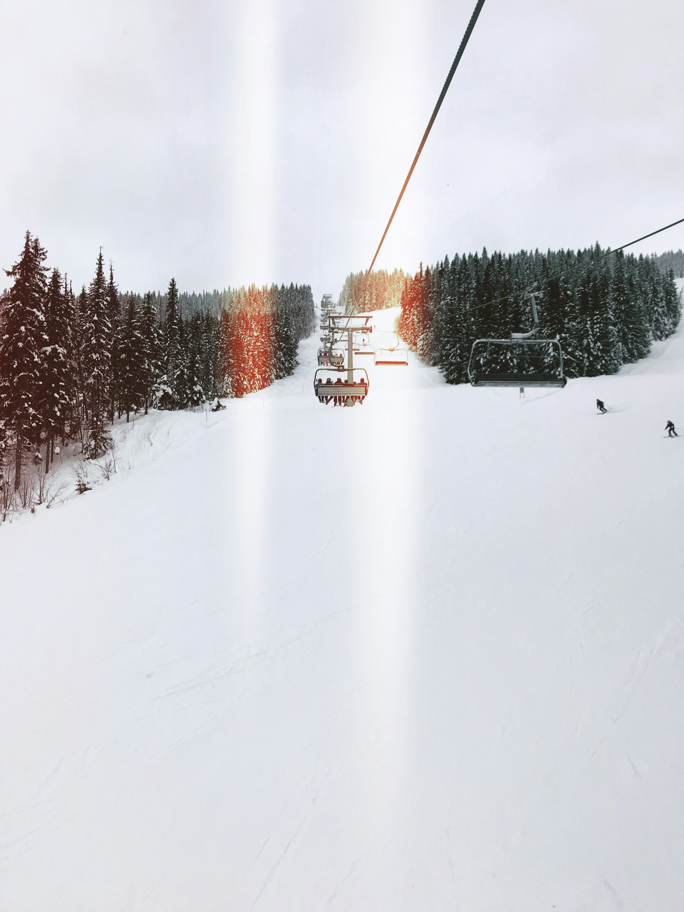 Two people ride in a ski lift over a snow-covered ski track in Trysil, Norway