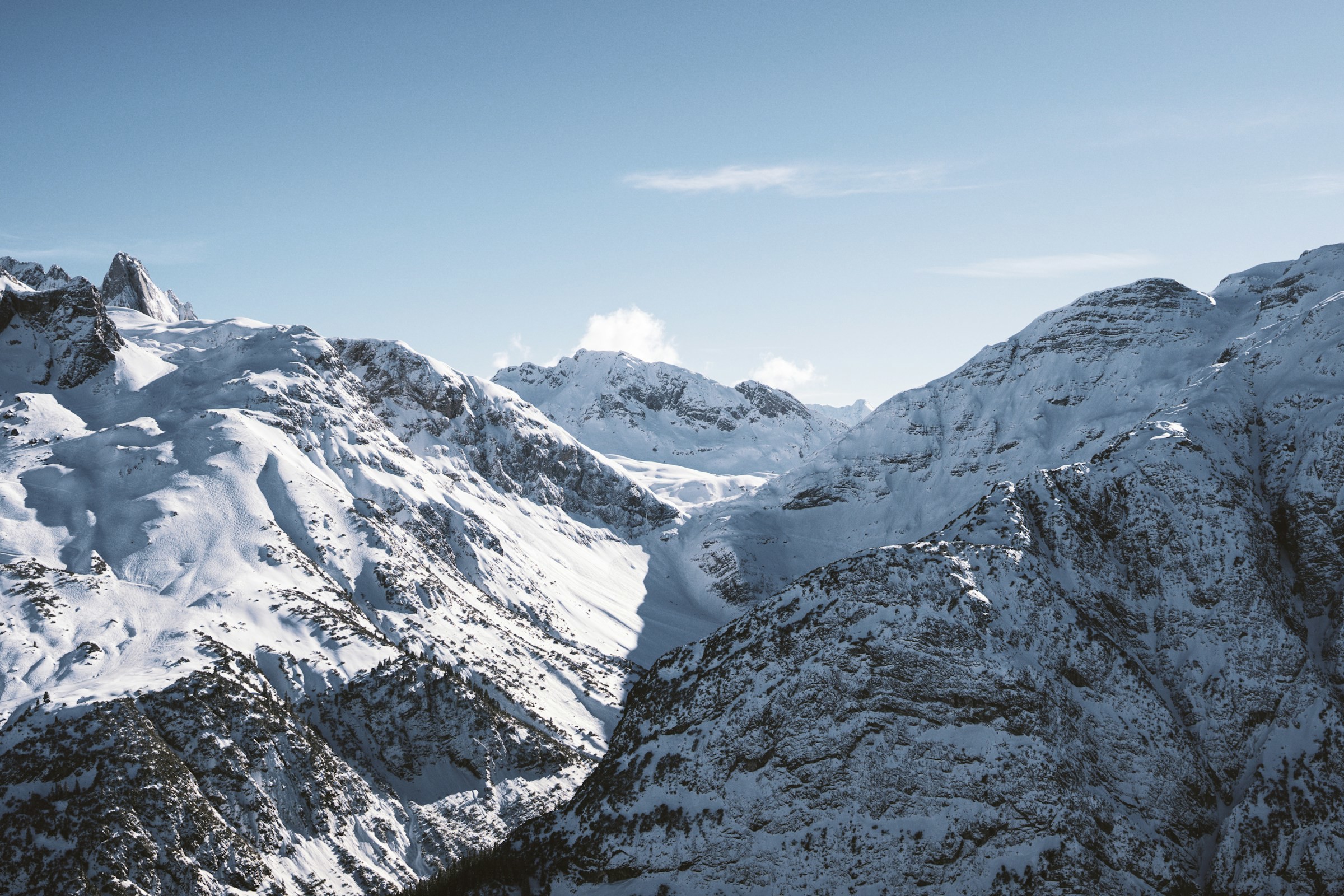 Snow-capped mountain peaks under clear skies, winter landscape in mountainous area.