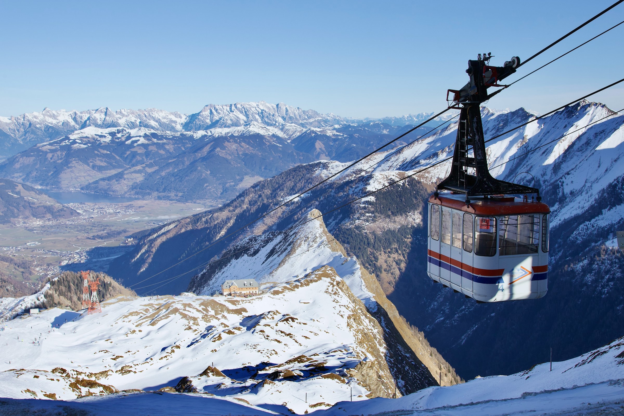 Ski lift descends a ski slope with mighty snow-capped mountains in the background in Zell am See