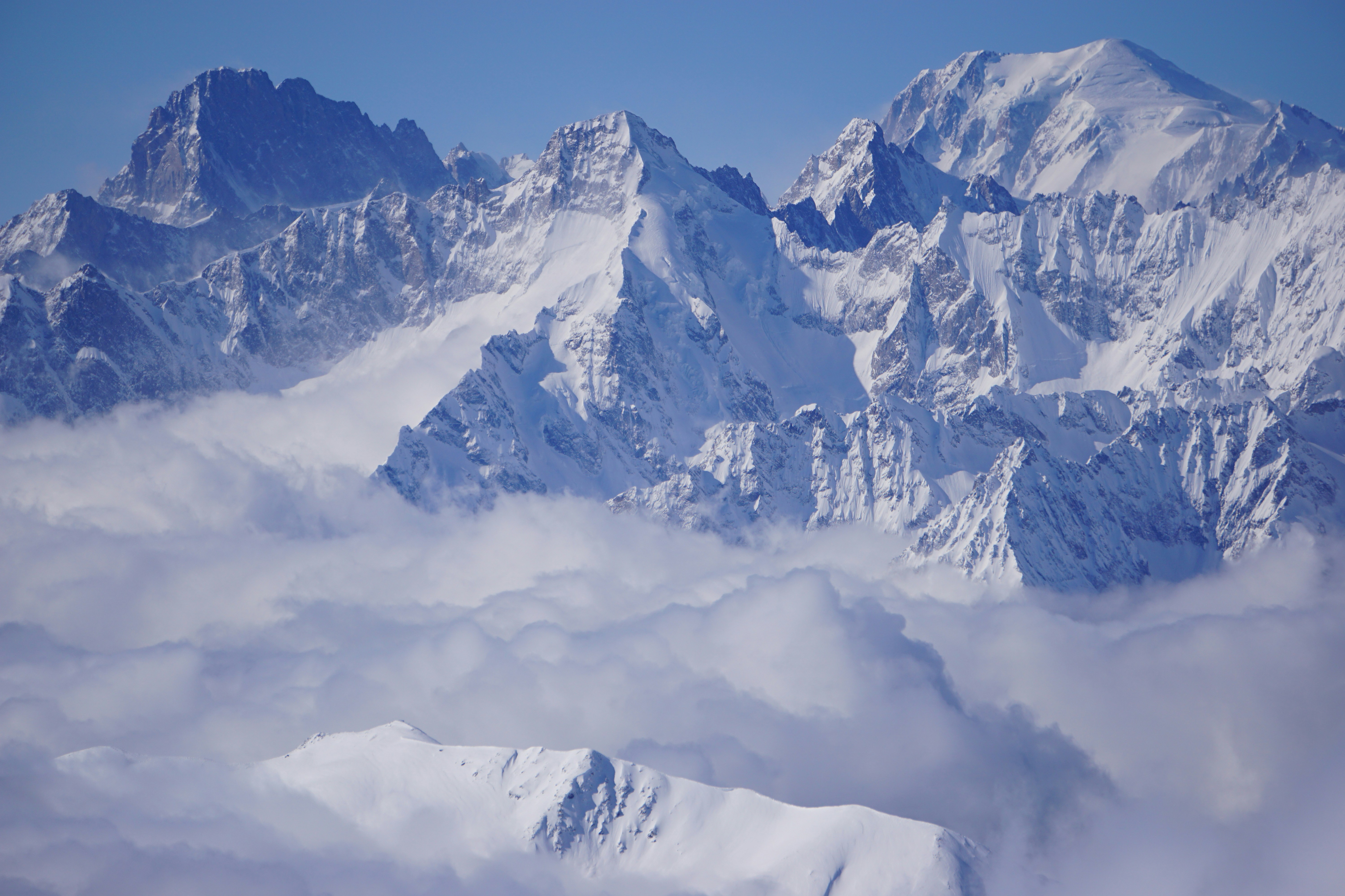 Travel to Verbier - Snow-capped mountain peaks towering above the clouds in a mountainous landscape.