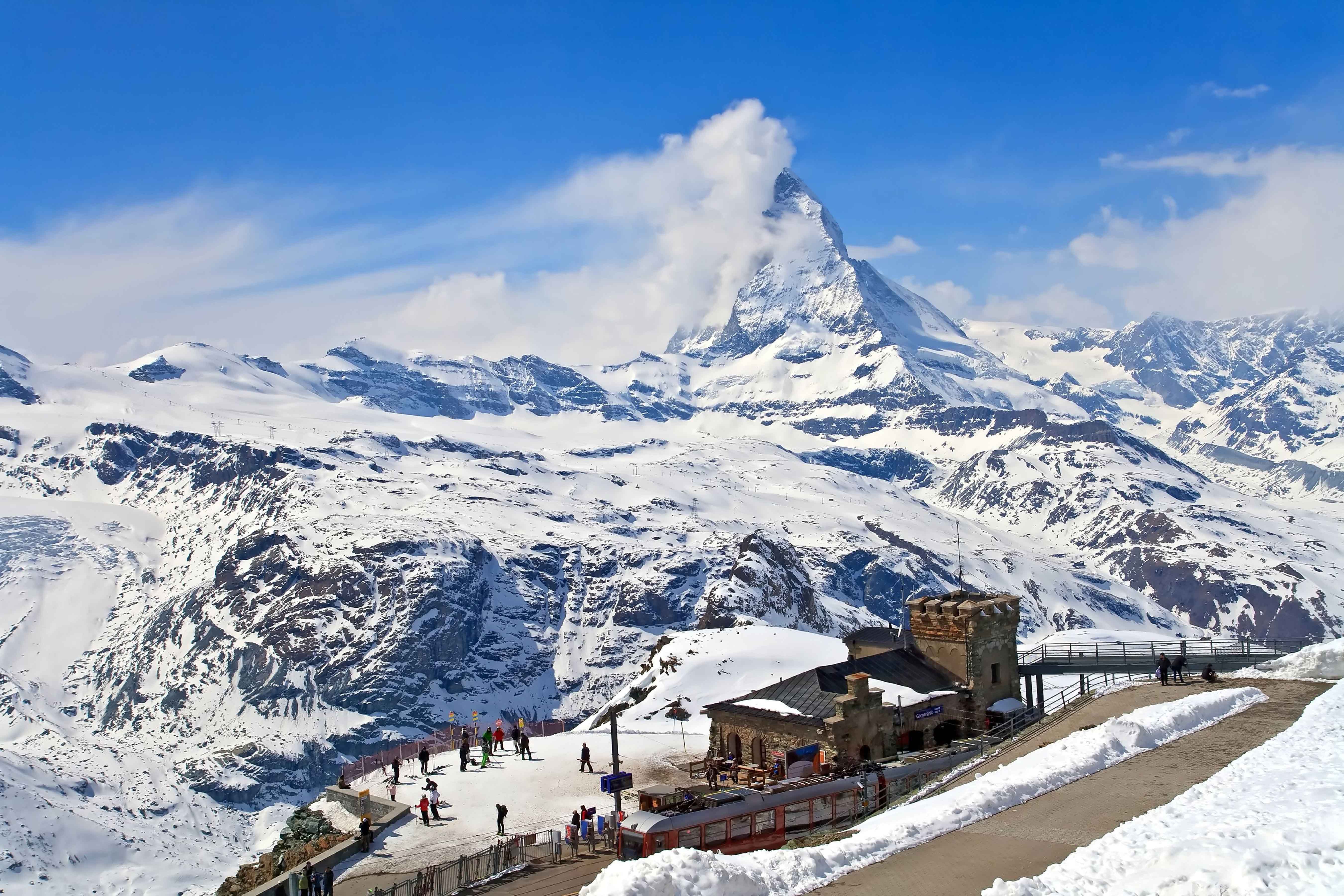 Travel to Zermatt - Majestic Matterhorn peak looming above Gornergrat ski area with tourists and snow-covered mountains in the Swiss Alps.