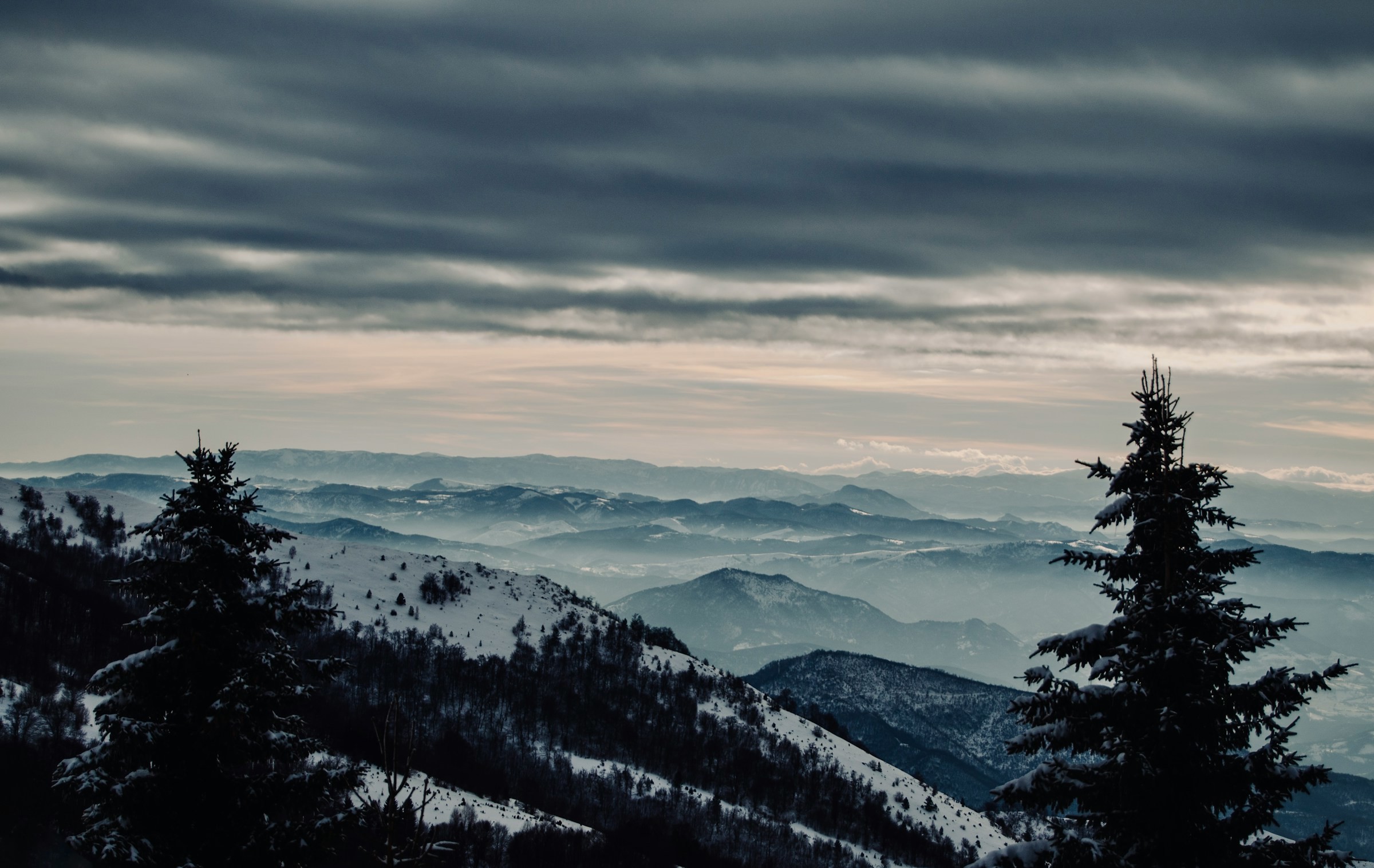 View of snow-capped mountains with trees and gray skies in the ski resort of Kopaonik, Serbia