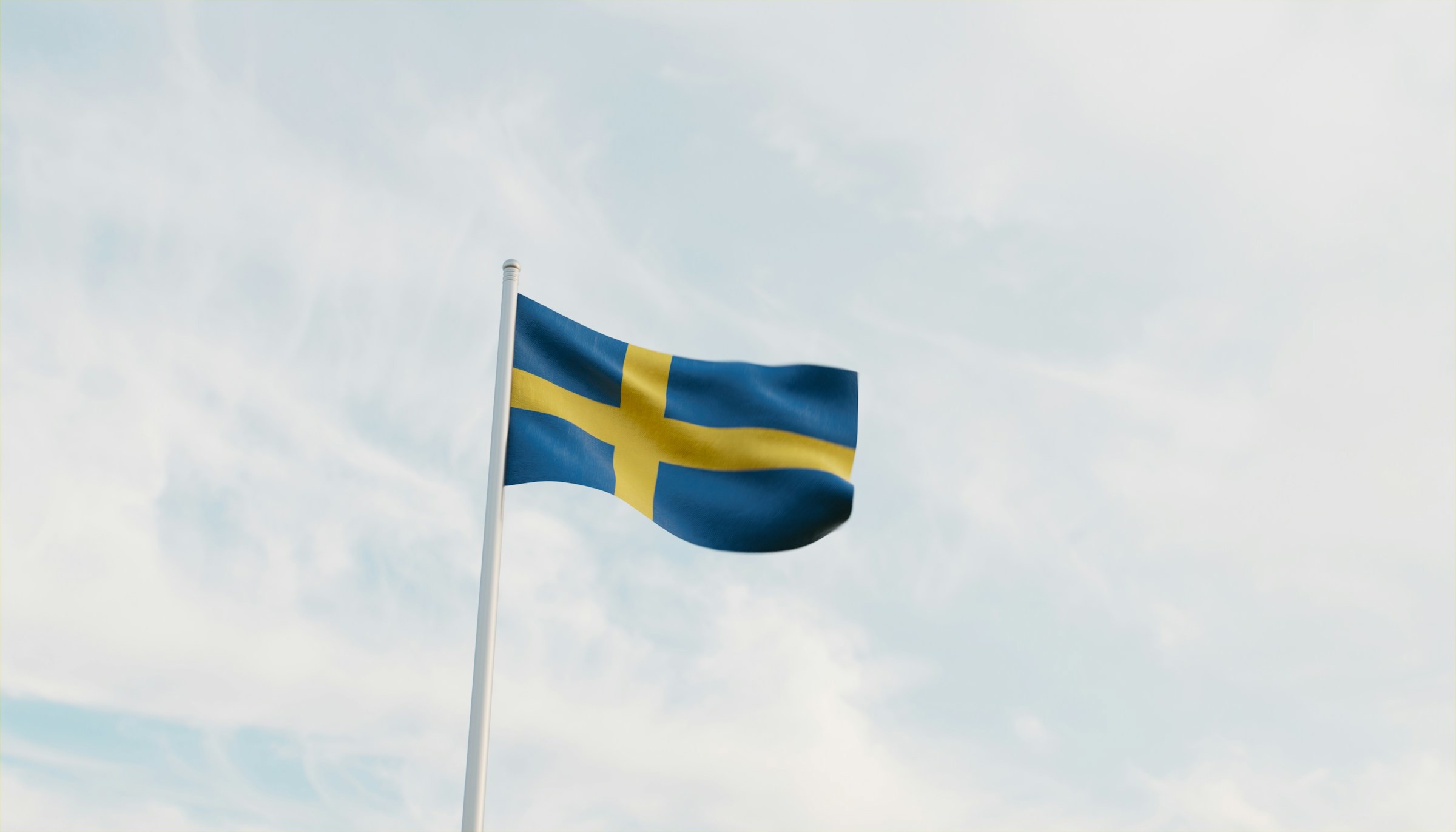 Swedish flag waving against a soft blue sky with light clouds