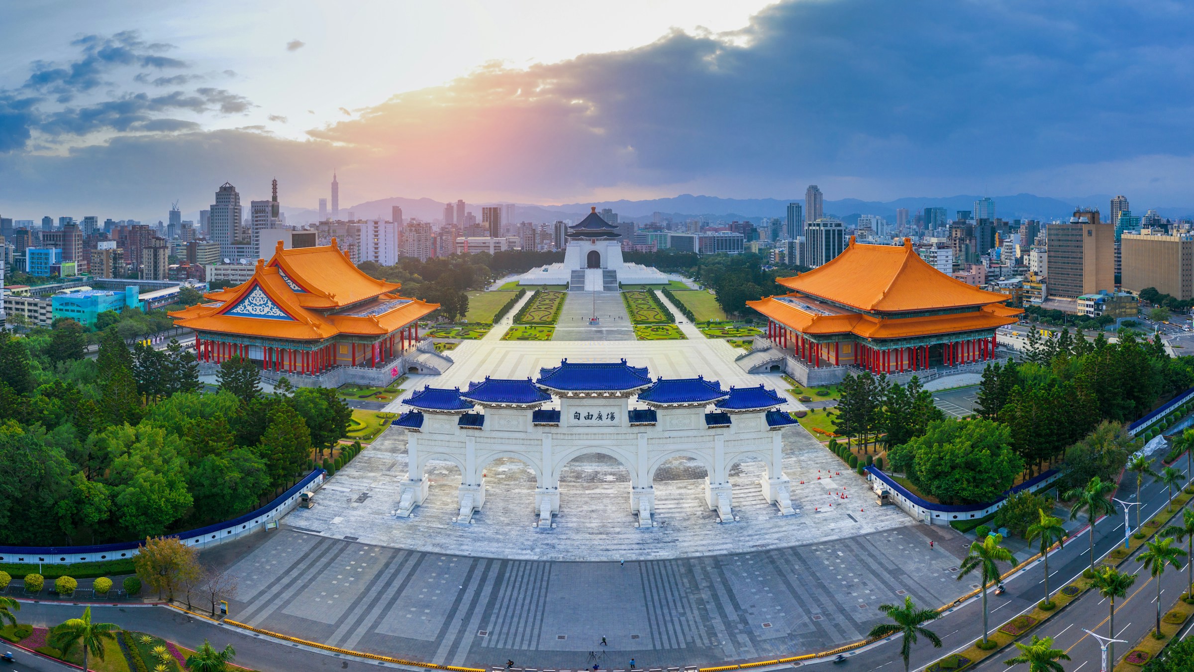 Panoramic view of Taipei squares and temples surrounded by greenery and a sunrise in the background