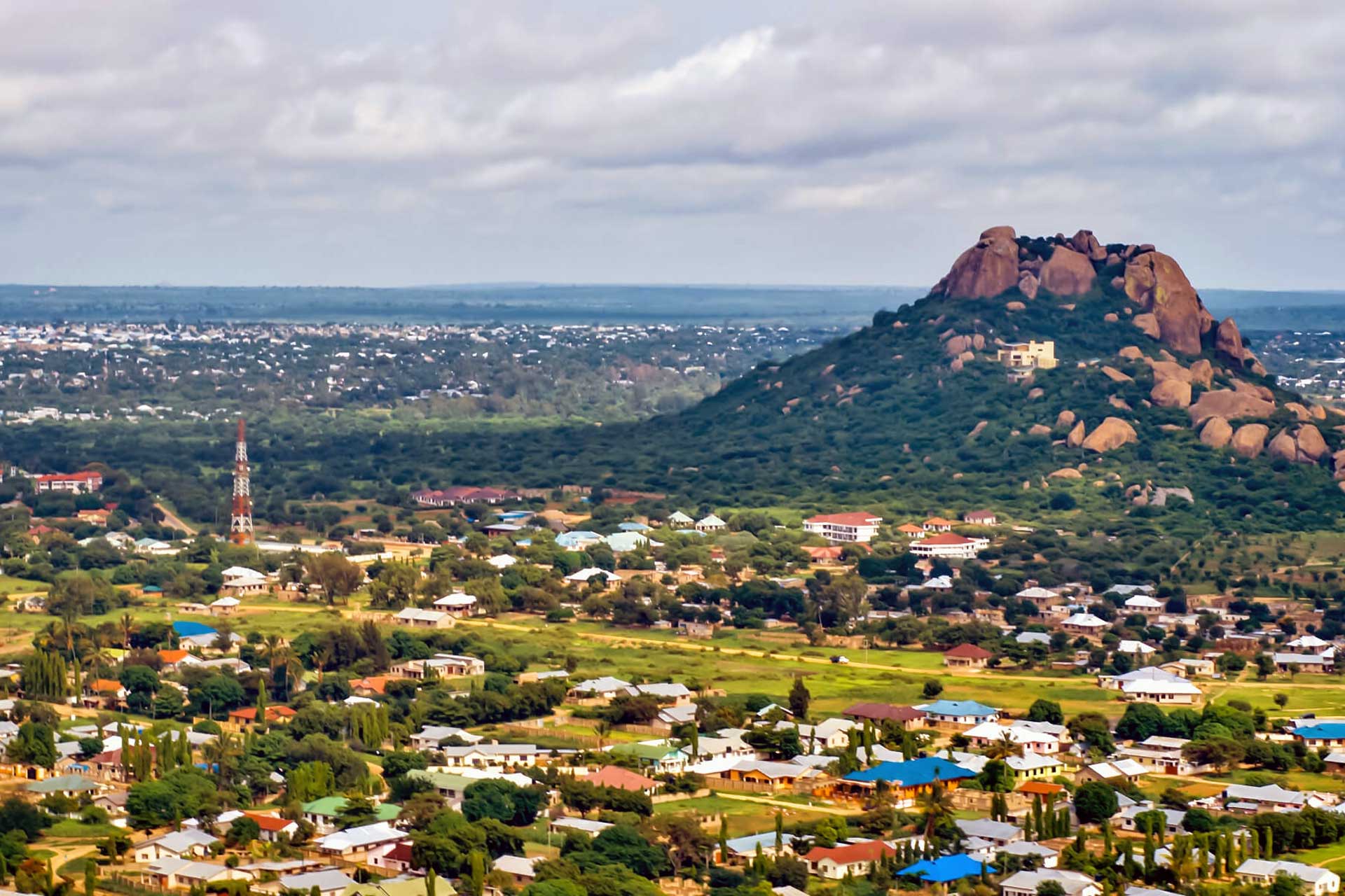 Reis til Dodoma - Utsikt ovenfra over Tanzanias hovedstad med grøntområder rundt og fjell og sletter i bakgrunnen