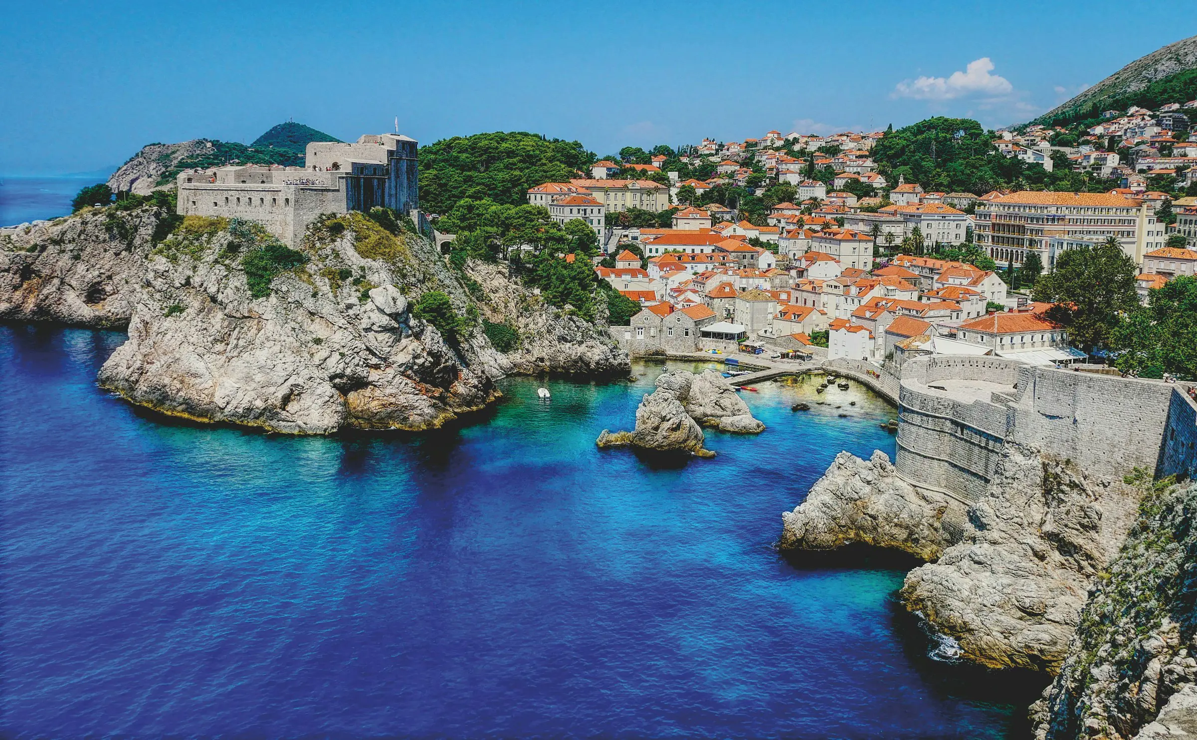 Flyfoto av Dubrovnik, Kroatia, som viser de historiske bymurene, steinbygningene med oransje tak, og det omkringliggende Adriaterhavet på en klar dag